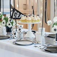 Graduation dessert table with gold graduation hat garland decorations
