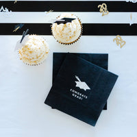 Graduation party setup with cupcakes and black “Congrats Grad” napkins