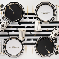 Graduation party table setup with black hexagon snack plates and striped table runner