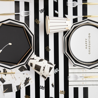 Graduation party table featuring black and white plates, cups, and graduation decorations
