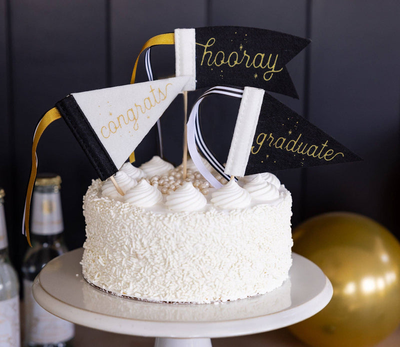 Graduation cake decorated with hooray congrats and graduate mini felt pennants
