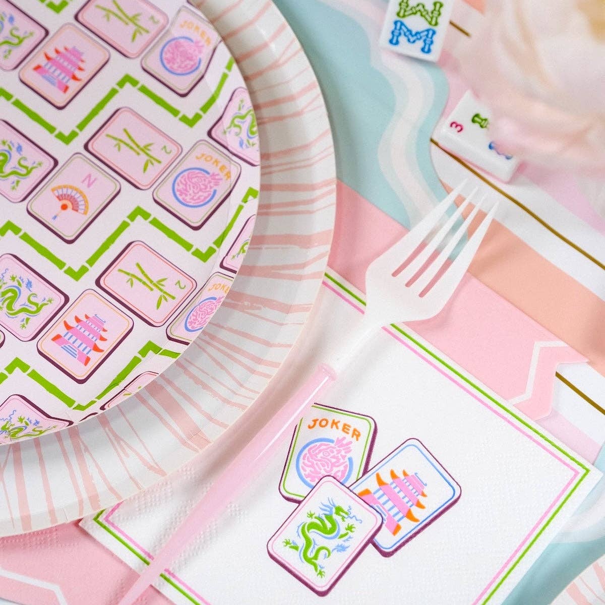 Tight close-up on the pink and green border of the Mahjong Cocktail Napkins next to game tiles.