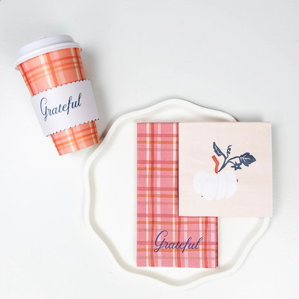 laid “Grateful” cup beside plaid guest towel and white-pumpkin cocktail napkin stacked on a white scalloped plate.