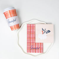laid “Grateful” cup beside plaid guest towel and white-pumpkin cocktail napkin stacked on a white scalloped plate.