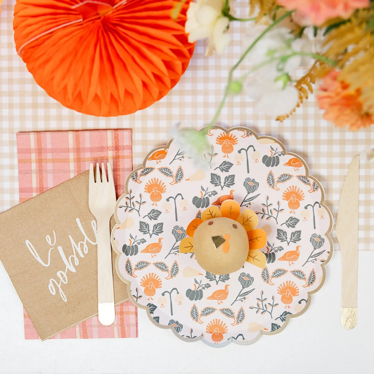 Overhead place setting on gingham with honeycomb pumpkin, plaid guest towel, and scalloped floral plate.