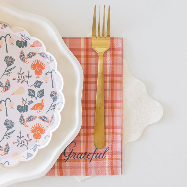 Gold fork resting on a plaid “Grateful” guest towel tucked under the plate edge.