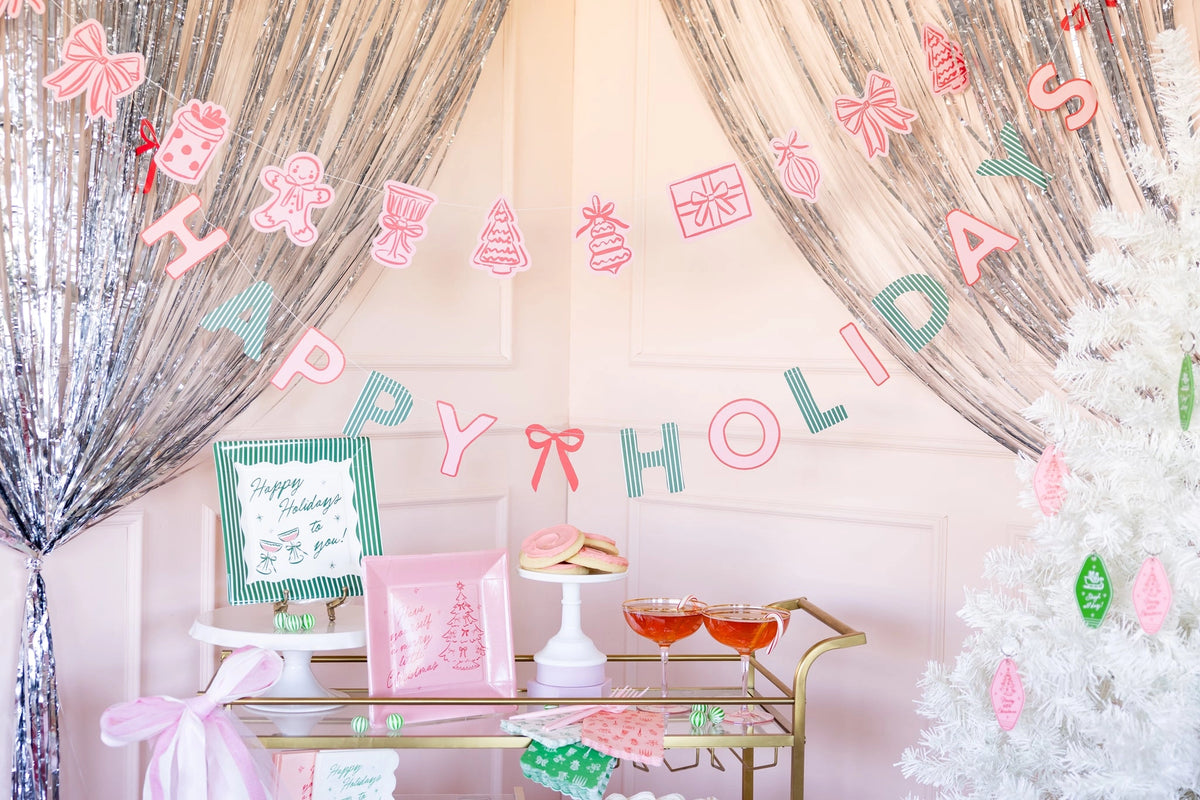Green Happy Holidays plates styled at a party backdrop with pink banner
