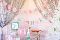 Green Happy Holidays plates styled at a party backdrop with pink banner