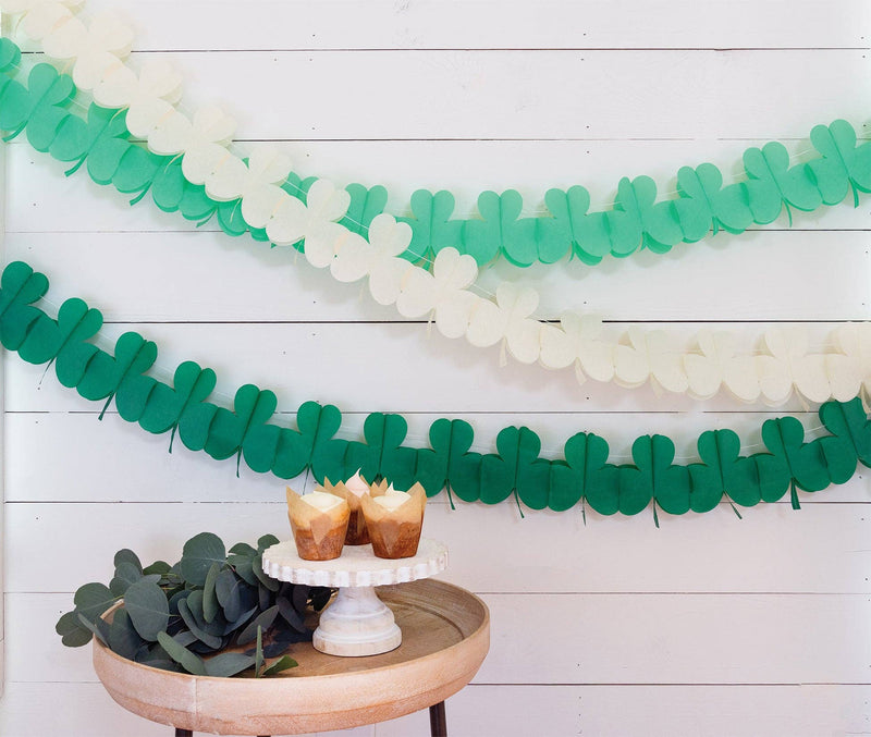 Green and cream shamrock paper garlands hanging on a white wood wall
