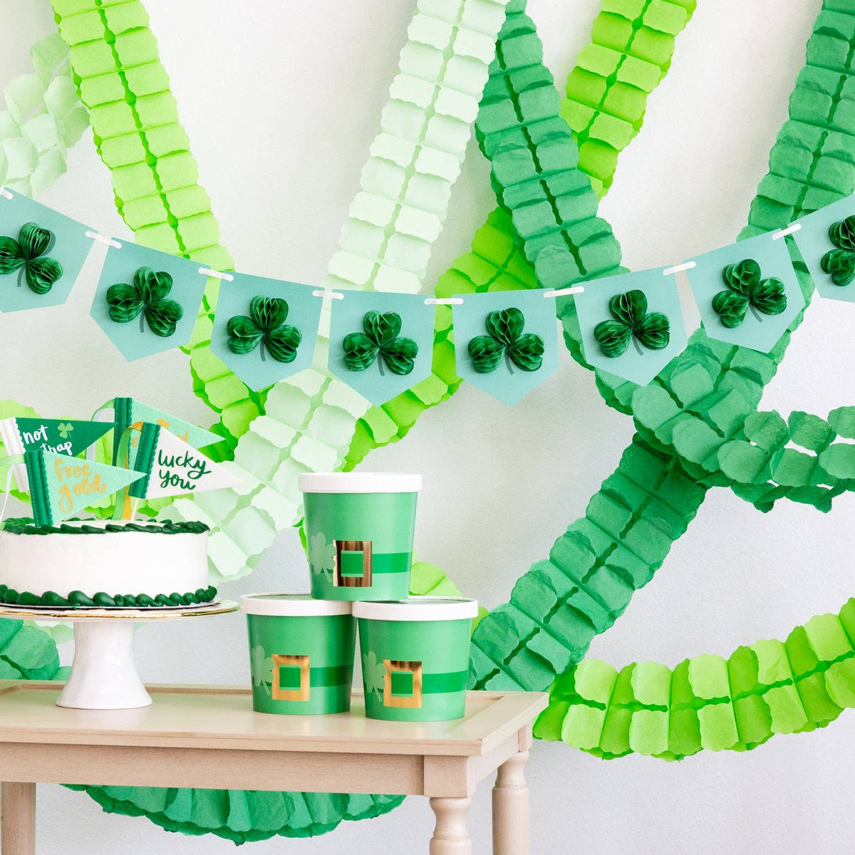 Green party backdrop featuring honeycomb shamrock banner and paper streamers