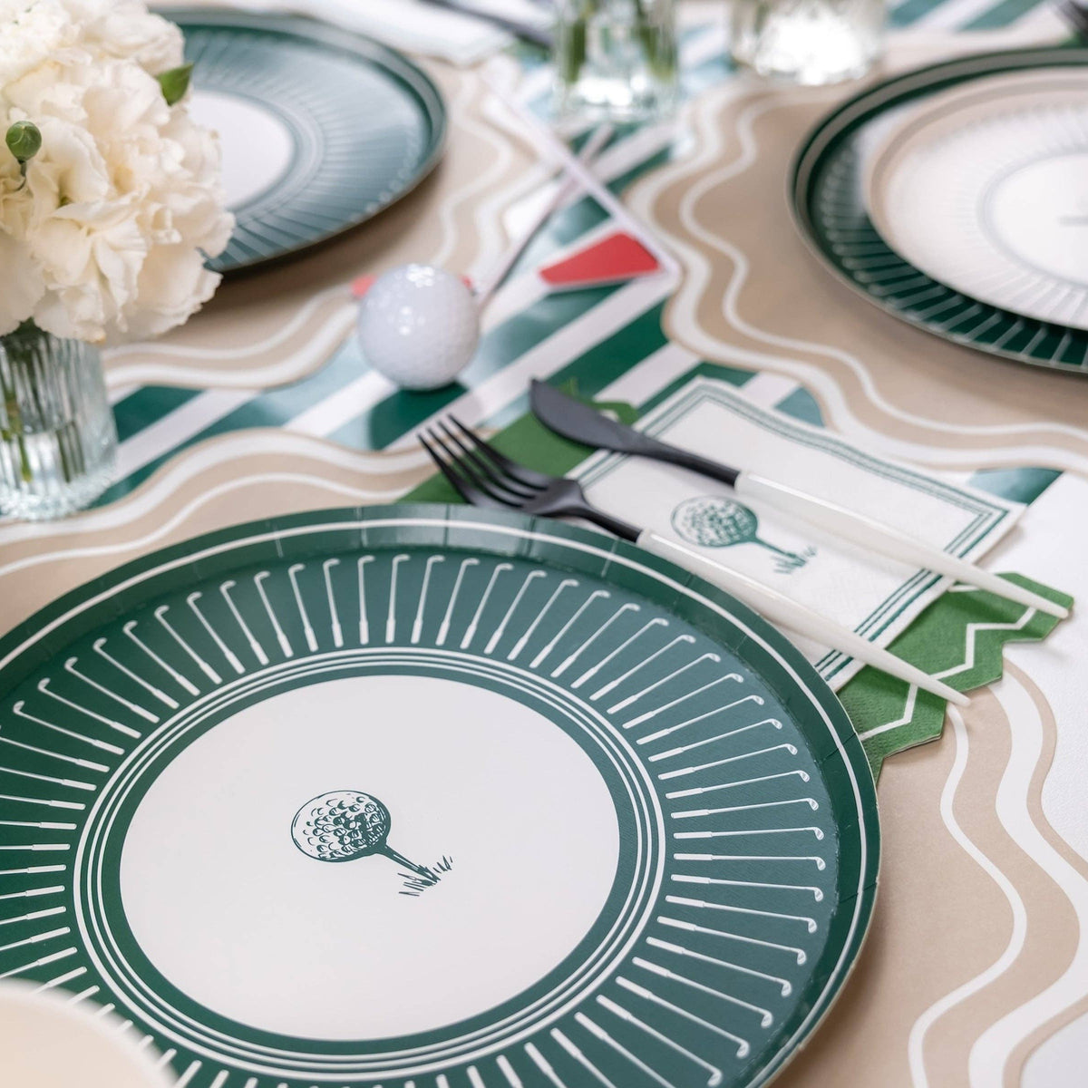 Close-up of green striped runner layered under golf party place settings
