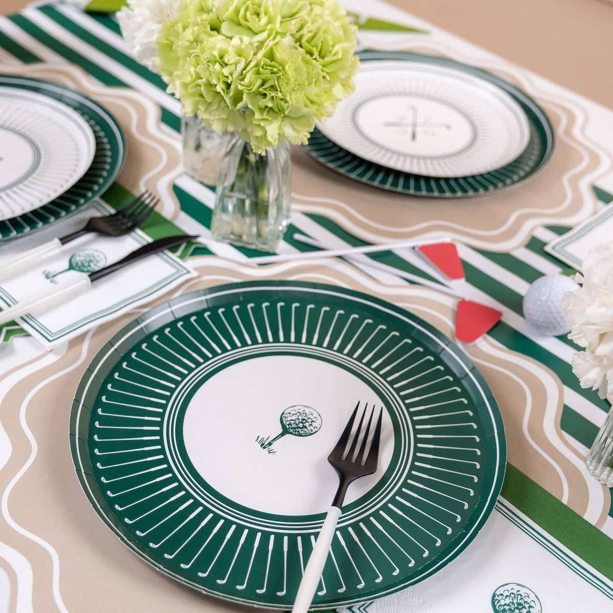 Golf-themed table setting with green striped runner, plates, and floral centerpieces