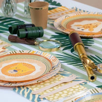 green striped paper table runner with safari table setup and party plates.