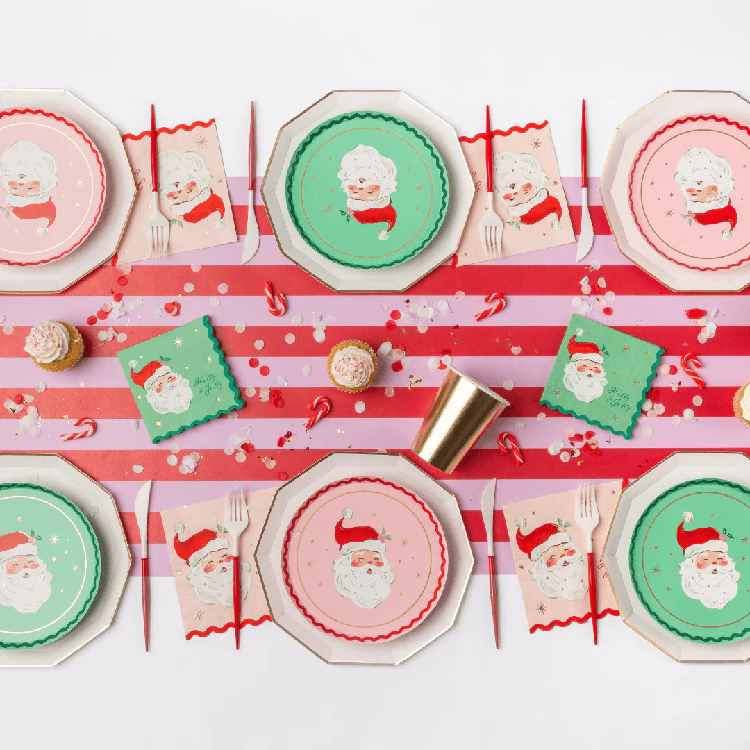 Retro Christmas table with pink and green Santa plates, Santa napkins, striped runner and gold cups