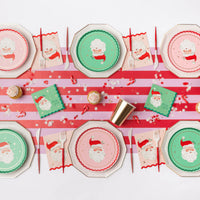 Retro Christmas table with pink and green Santa plates, Santa napkins, striped runner and gold cups
