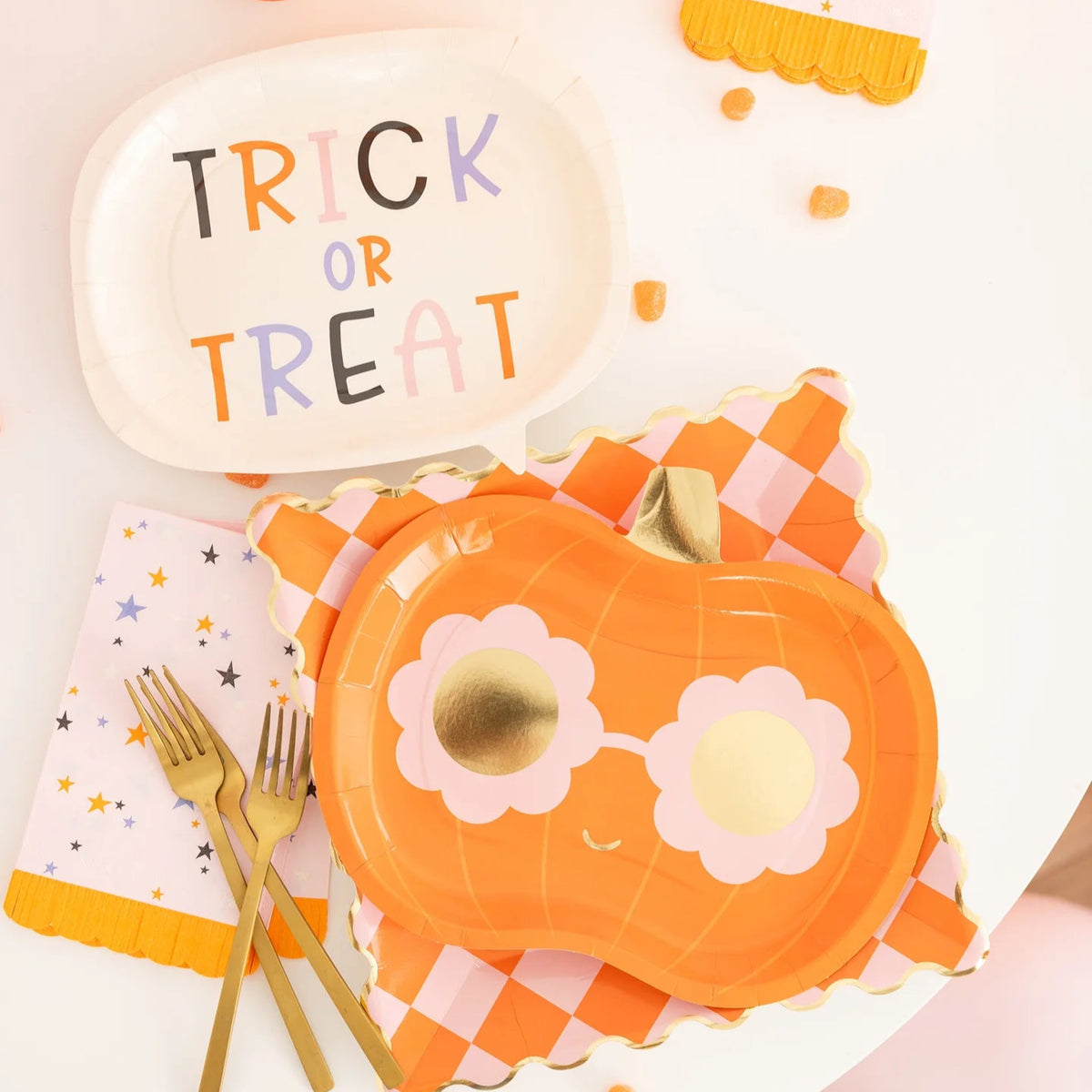 Halloween-themed table setting with a pumpkin plate, 'Trick or Treat' sign, and gold forks.