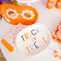 Close-up dessert bar showing word-bubble plate beside pumpkin treat boxes and cups, highlighting cohesive retro orange, lilac, and gold palette.