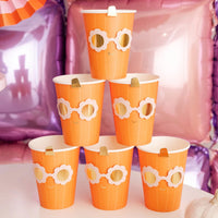Pyramid of Groovy Pumpkin cups on party table; metallic sunglasses design and gold stems pop against pink-purple balloon wall and striped fans.
