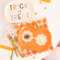 Pastel star napkin styled with pumpkin sunglasses plate, gingham charger and “Trick or Treat” speech-bubble dish on bright dessert table.