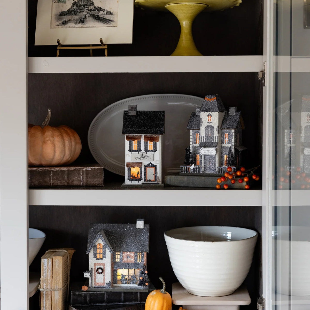 Another shelf vignette featuring the Haberdashery haunted house and coordinating glitter houses for a cozy Halloween display.