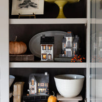 Another shelf vignette featuring the Haberdashery haunted house and coordinating glitter houses for a cozy Halloween display.
