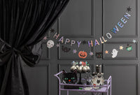 Both banners hung across a dark gray paneled wall above a Halloween party treat station with black curtains, white balloon garland, and ghost decorations.