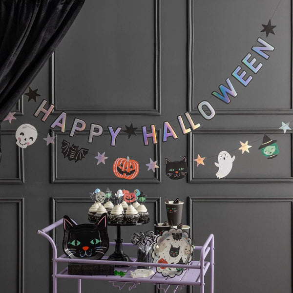 Both banners hung across a dark gray paneled wall above a Halloween party treat station with black curtains, white balloon garland, and ghost decorations.