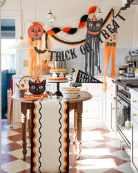 Vintage Halloween kitchen with the orange black and cream crepe garland swagged above a wavy runner and dessert table