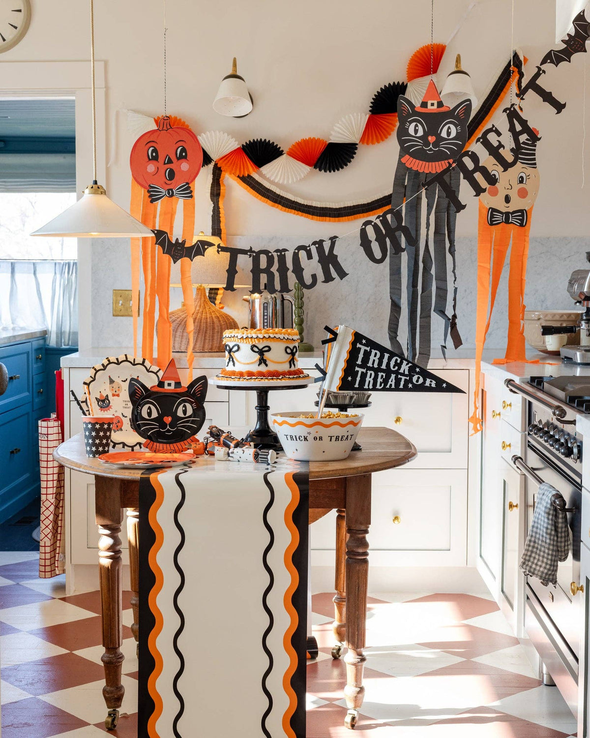 Halloween crepe streamer garland hung with pumpkin and black cat hanging decorations in a styled kitchen