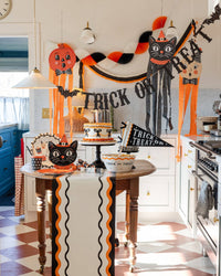 Halloween crepe streamer garland hung with pumpkin and black cat hanging decorations in a styled kitchen