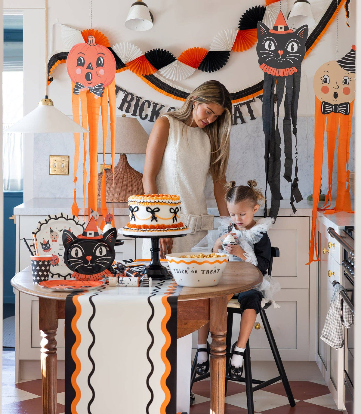 Woman and child at a Halloween-themed birthday party with decorations and cake featuring vintage halloween character picks.