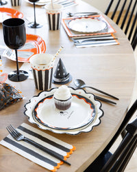 Halloween dinner napkins styled on a Halloween place setting with matching cups and straws.