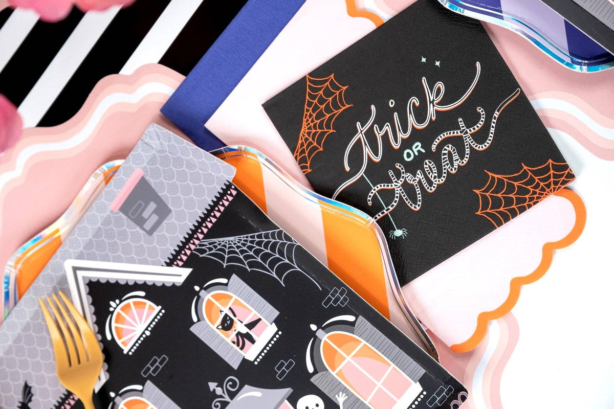 Halloween party table detail showing the trick or treat napkin, witch-themed plates, and orange spiderweb elements.