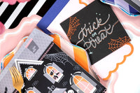 Halloween party table detail showing the trick or treat napkin, witch-themed plates, and orange spiderweb elements.