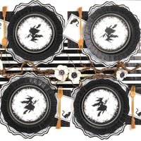 Halloween place setting with the black guest towel under a witch plate, gold flatware, on a black-and-white striped surface.