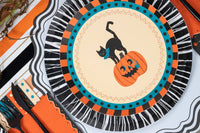 Halloween place setting showing the vintage cat plate layered on a black fringe charger with orange accents.