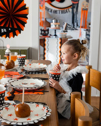 Child at a Halloween-themed dining table with decorations and treats using a halloween reusable straw.