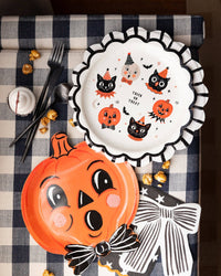 Vintage Halloween tablescape featuring striped scalloped plate as a charger plate, pumpkin shaped plate, black bow napkin, and Halloween icon plate