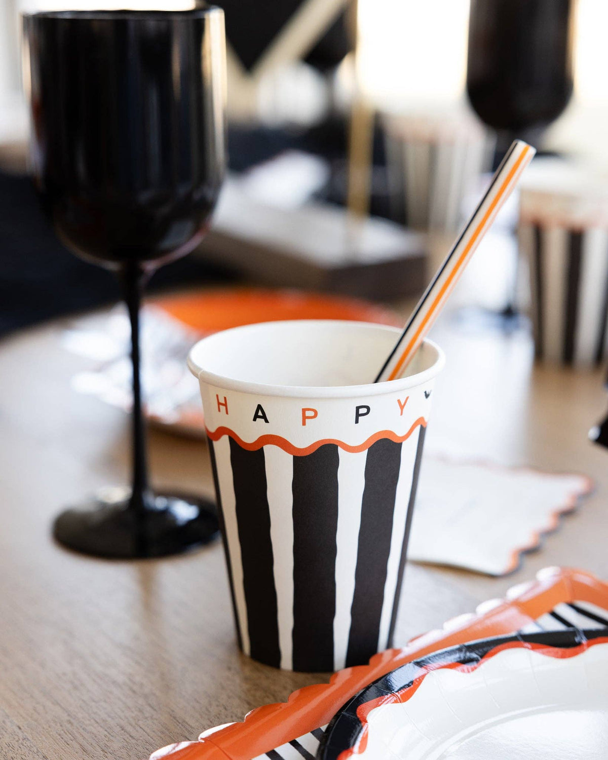 Striped cup with 'HAPPY HALLOWEEN' text on a table with a blurred background