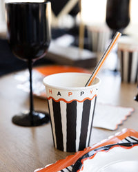 Striped cup with 'HAPPY HALLOWEEN' text on a table with a blurred background