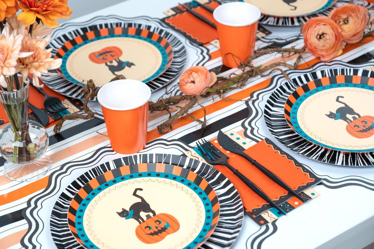 Halloween table detail showing the orange napkins layered with vintage rosette plates and orange cups.