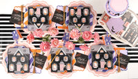 Overhead Halloween tablescape — pink scalloped chargers, trick or treat napkins, purple and orange plates, and florals across a black-and-white striped runner.
