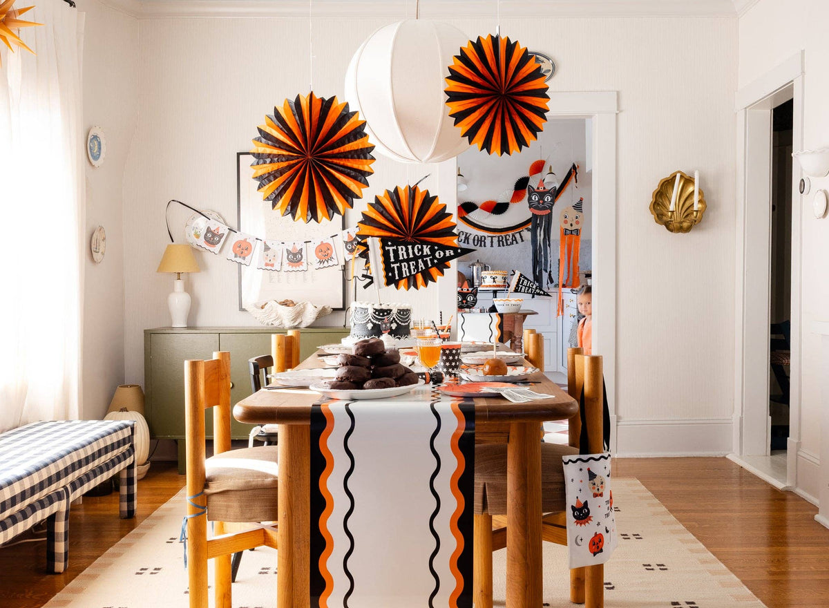 Dining room with Halloween decorations, including Halloween tissue paper fans and a 'Trick or Treat' banner.