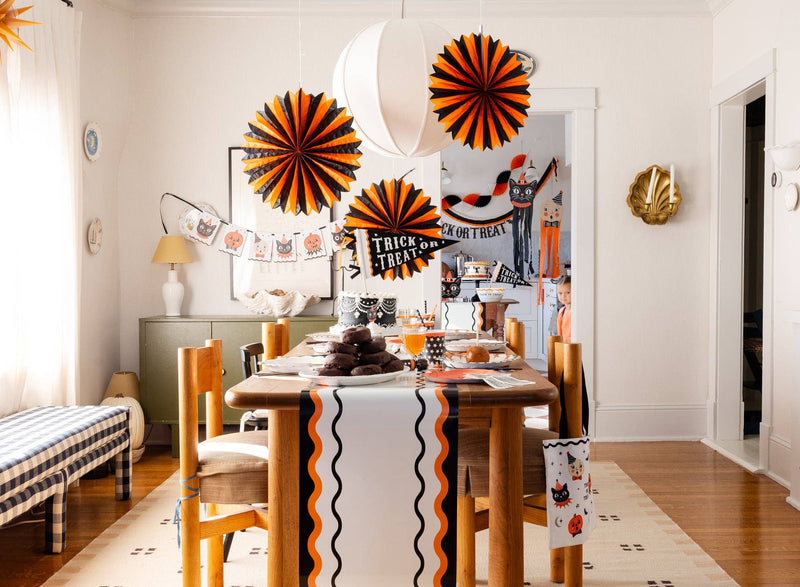 Dining room with Halloween decorations, including Halloween tissue paper fans and a 'Trick or Treat' banner.