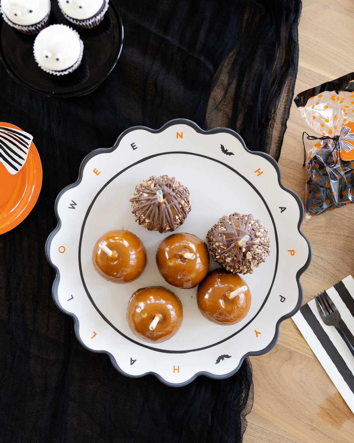 The Halloween tray styled on a black surface holding cupcakes and treats at a party, with fall décor around it.