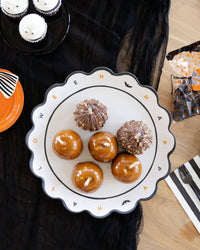 The Halloween tray styled on a black surface holding cupcakes and treats at a party, with fall décor around it.