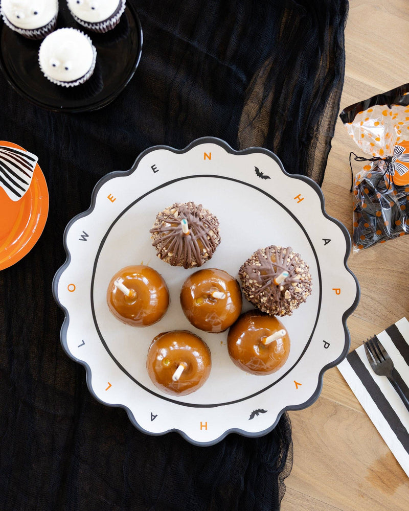 The Halloween tray styled on a black surface holding cupcakes and treats at a party, with fall décor around it.