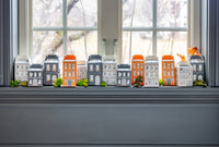 Wide windowsill scene with all 13 Halloween village treat boxes lined up to create a street of houses; ideal for party favors or Halloween countdown.