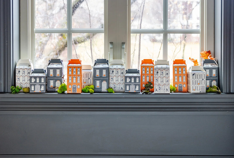 Wide windowsill scene with all 13 Halloween village treat boxes lined up to create a street of houses; ideal for party favors or Halloween countdown.