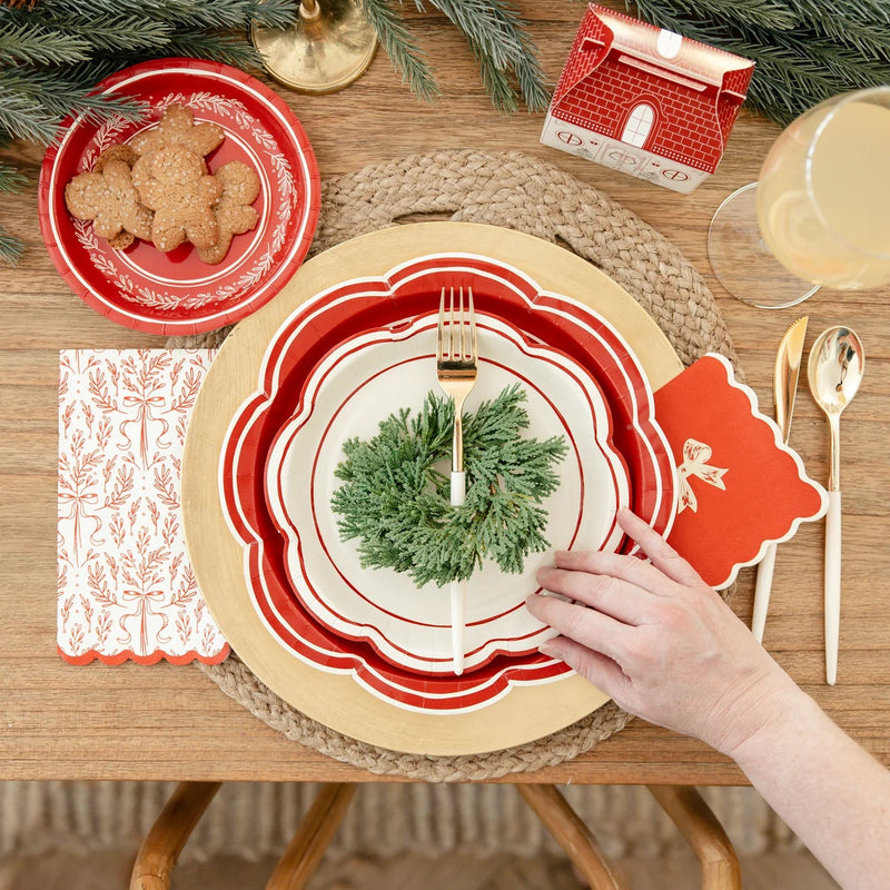 Hand near the stacked scalloped edge plates at a place setting, highlighting the layered look.